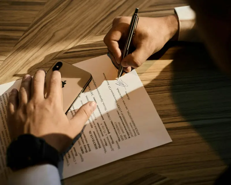 Cliente assinando um contrato sobre mesa de madeira
